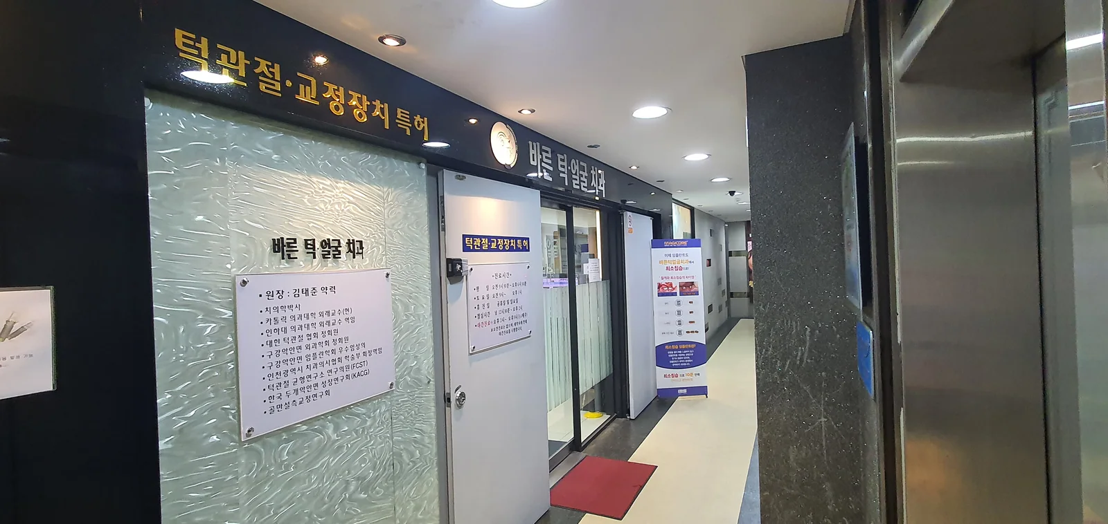바른턱얼굴치과의원 복도 — 입구 명판과 진료실로 이어지는 통로